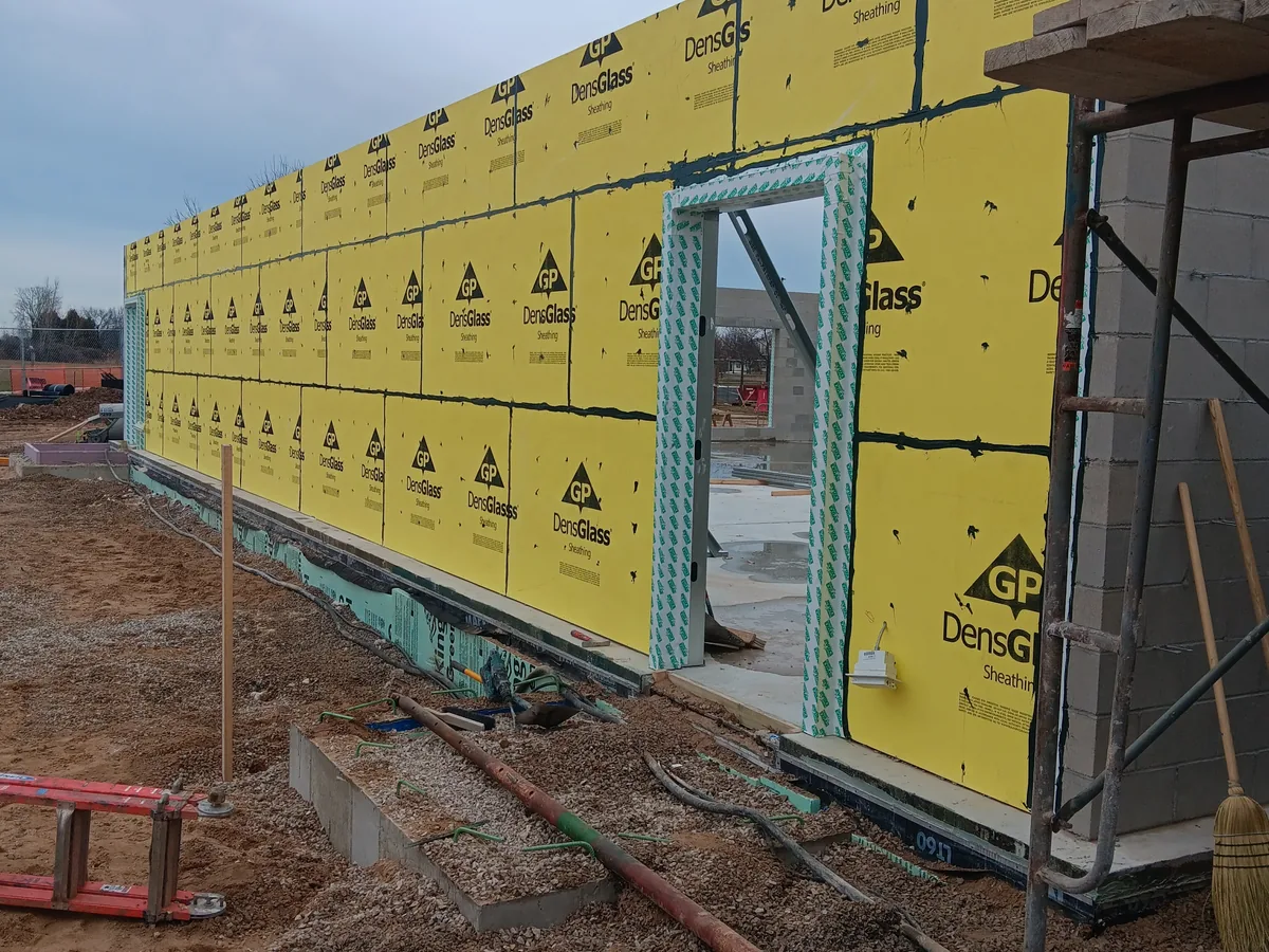 Exterior wall sheathing with a green fluid applied air and vapor barrier around window openings