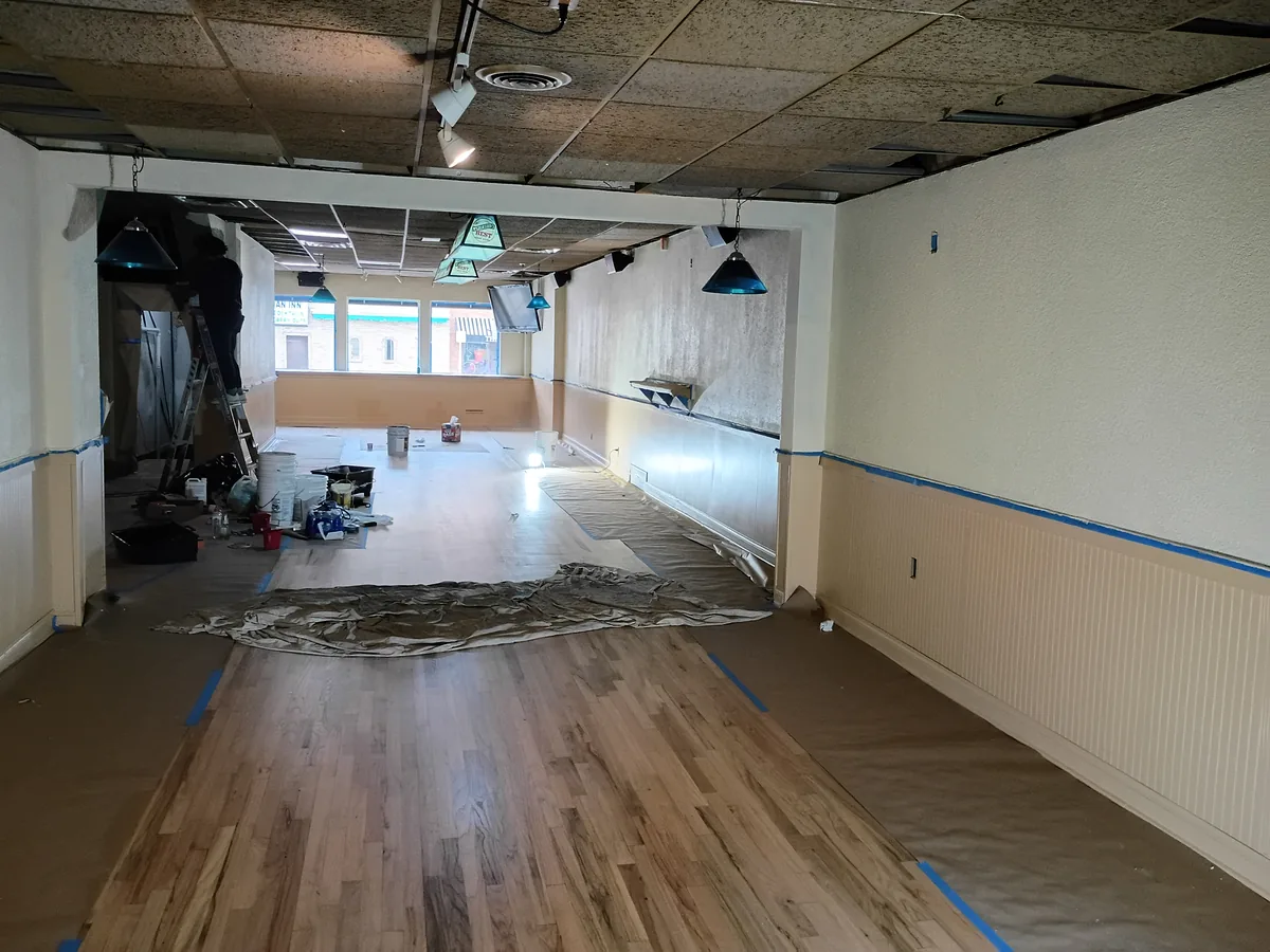 Commercial interior with drop cloths and taped trim during painting and floor work