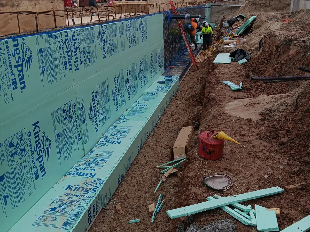 Rigid insulation board installed over a waterproofed foundation wall in an open trench