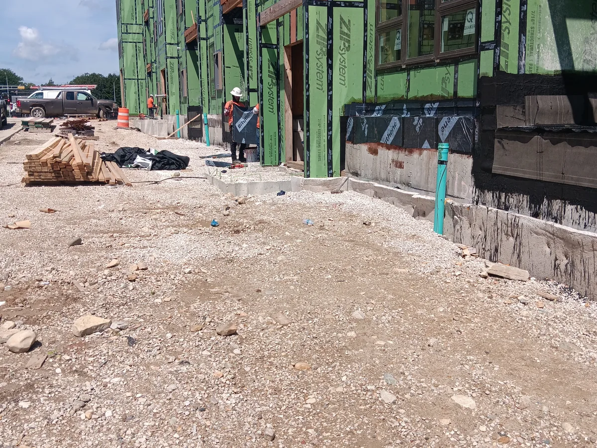 New home with exterior sheathing and a black waterproofing coating along the foundation